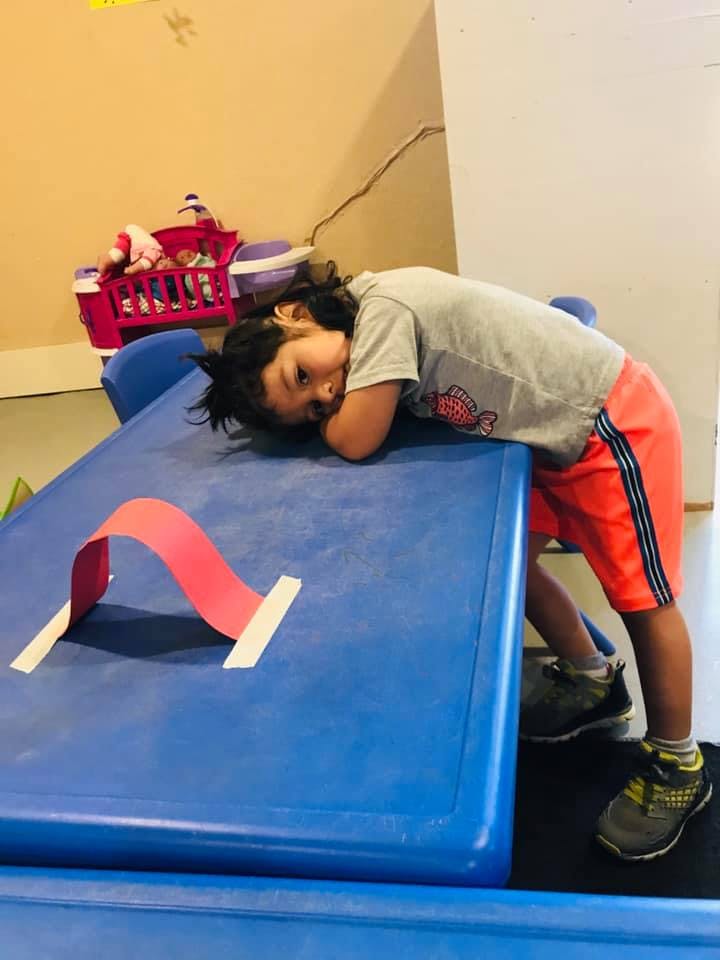 Child resting head on blue surface