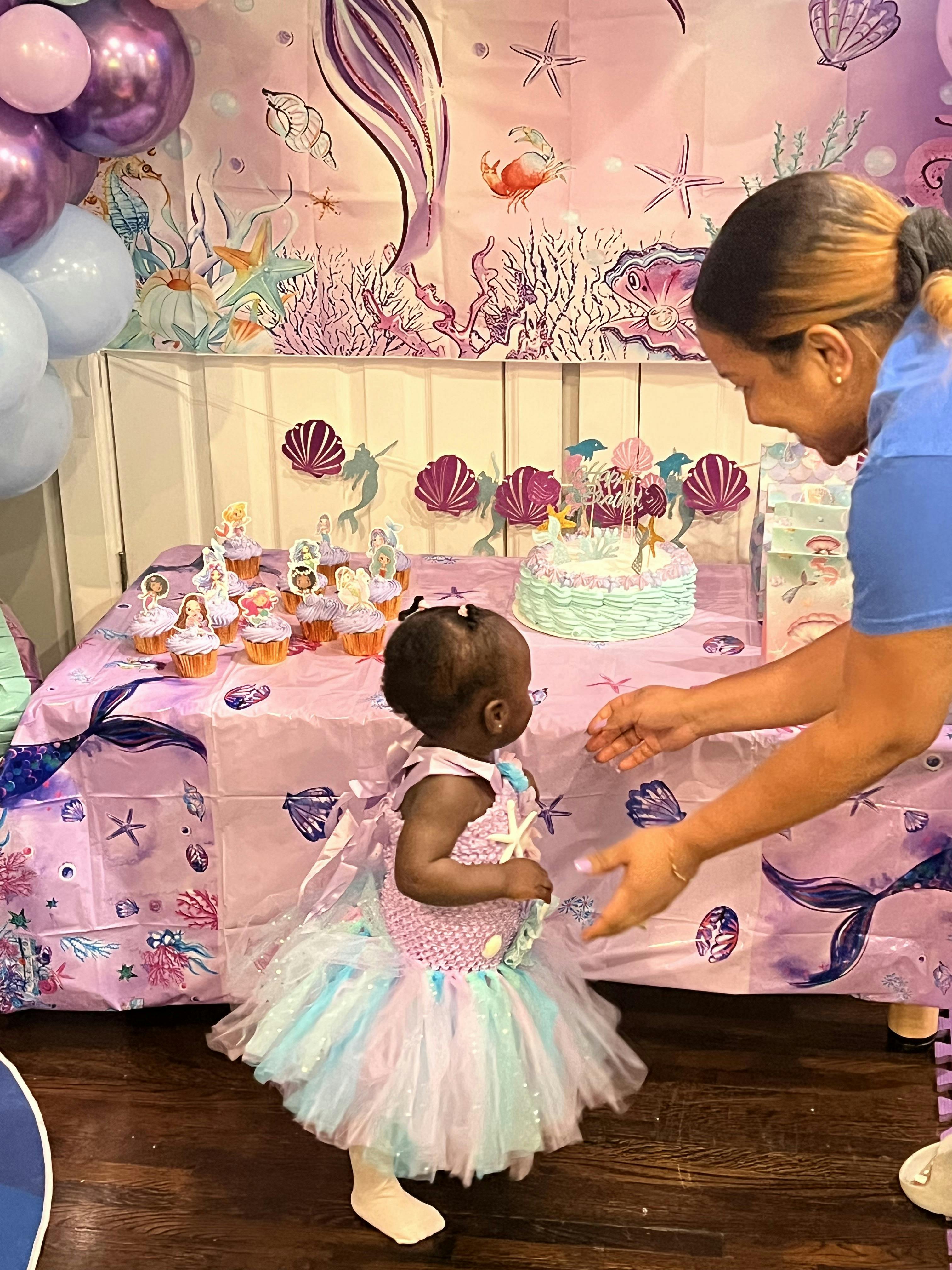 Person and child at a table with a cake and cupcakes