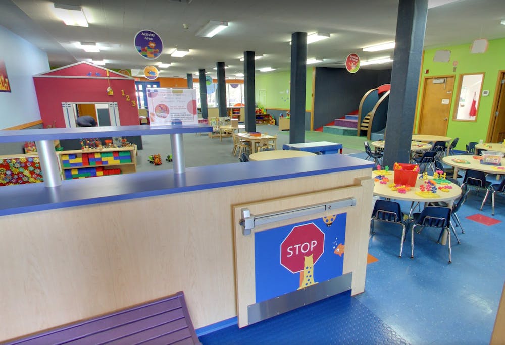 Indoor play area with small tables and chairs, playhouse, and a stop sign