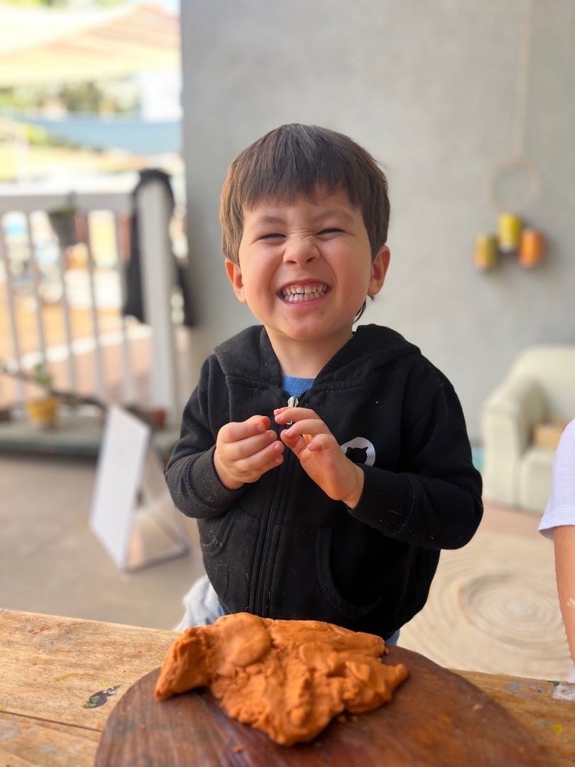 Child making a funny face while holding playdough