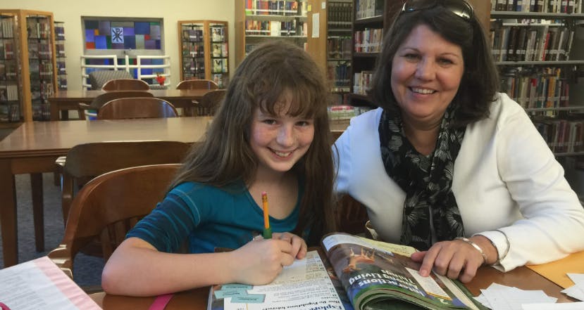 Person and child looking at a book in a library