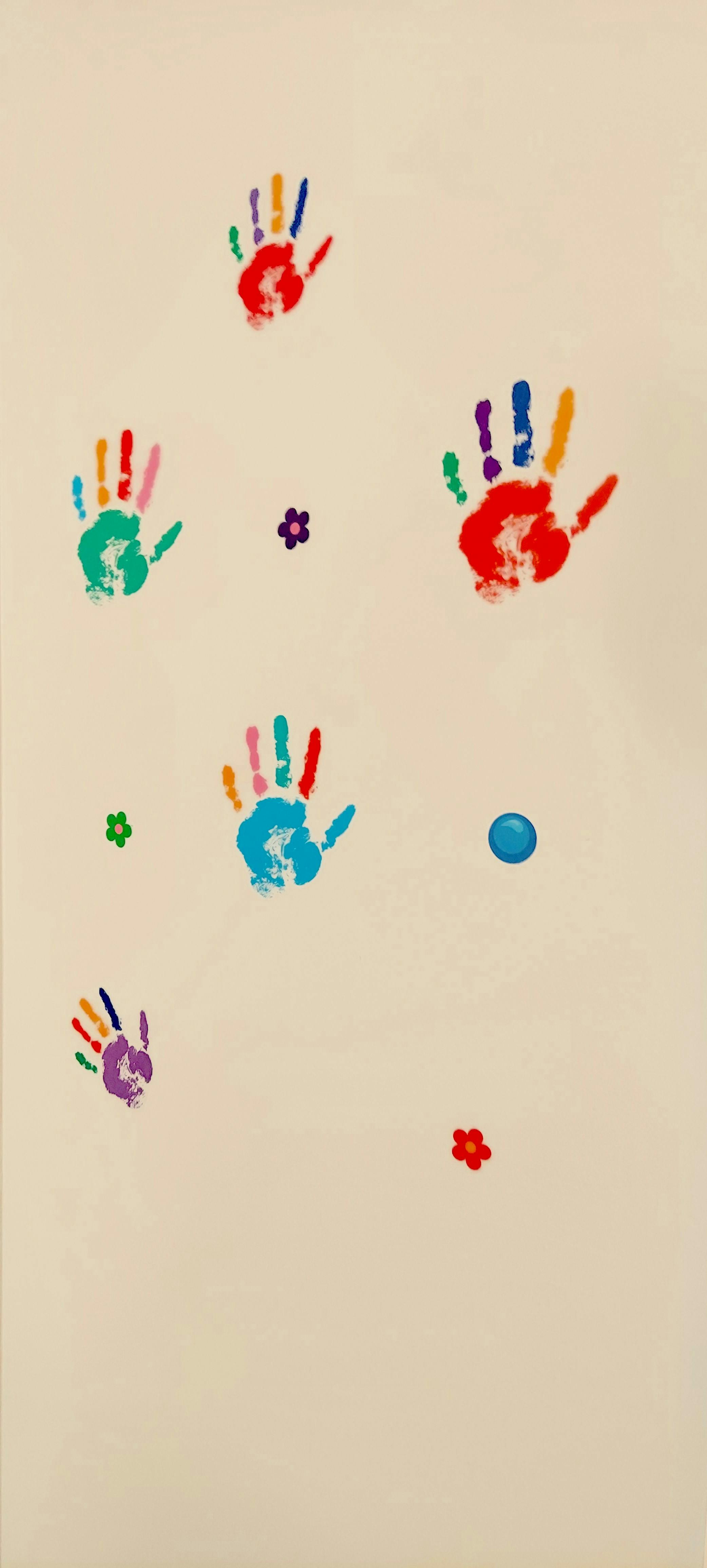 Multiple colorful handprints and small flower shapes on a light background