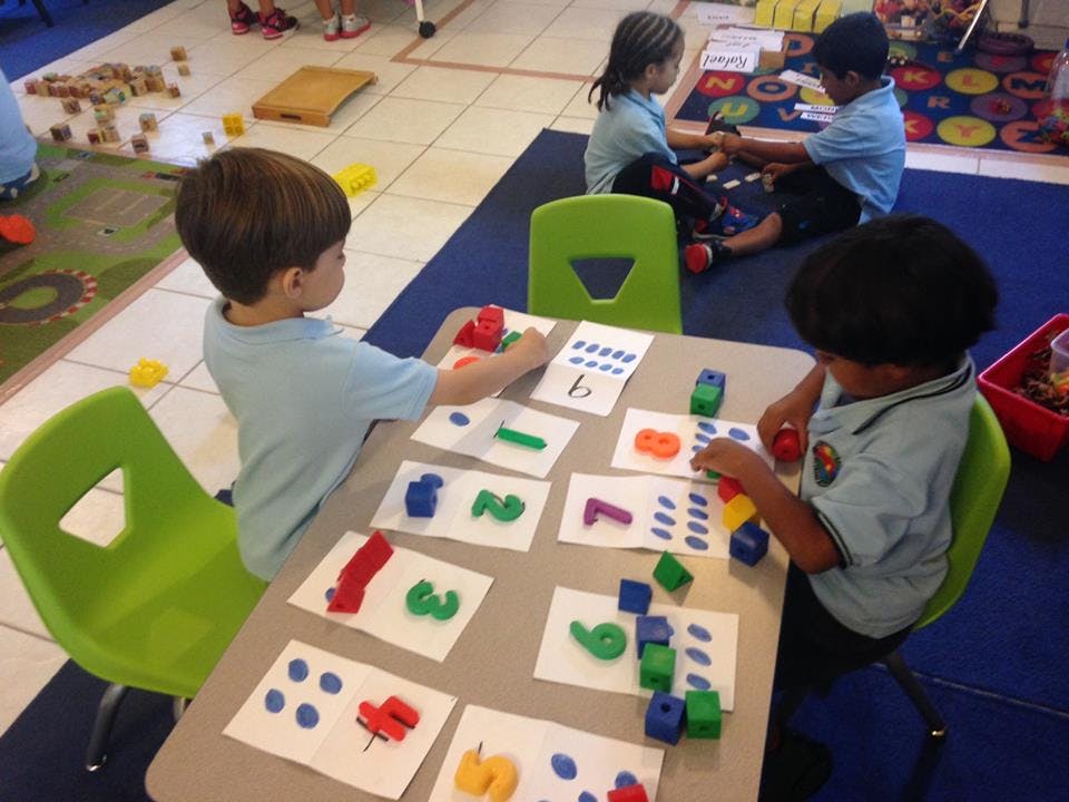 Children learning numbers with playdough and blocks at a table