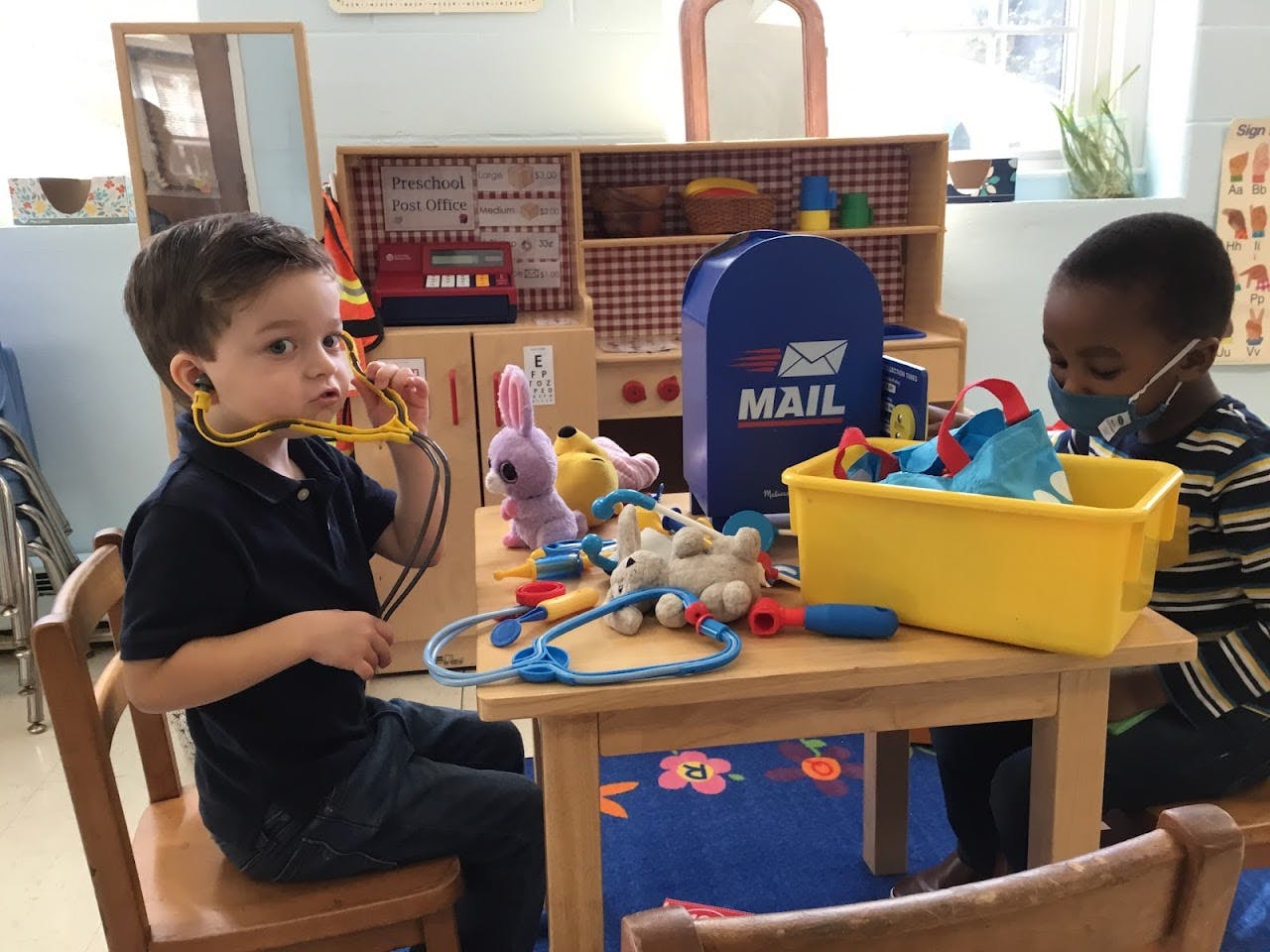 Two children playing with toy medical instruments at a table