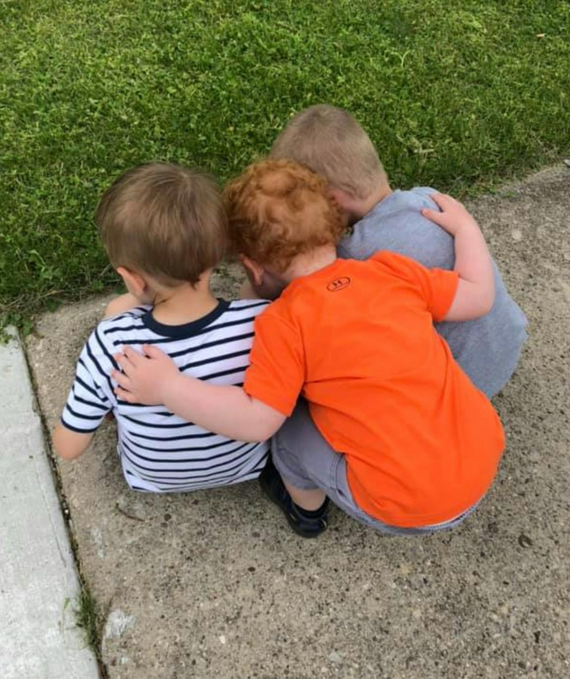 Three children huddled together, seen from behind