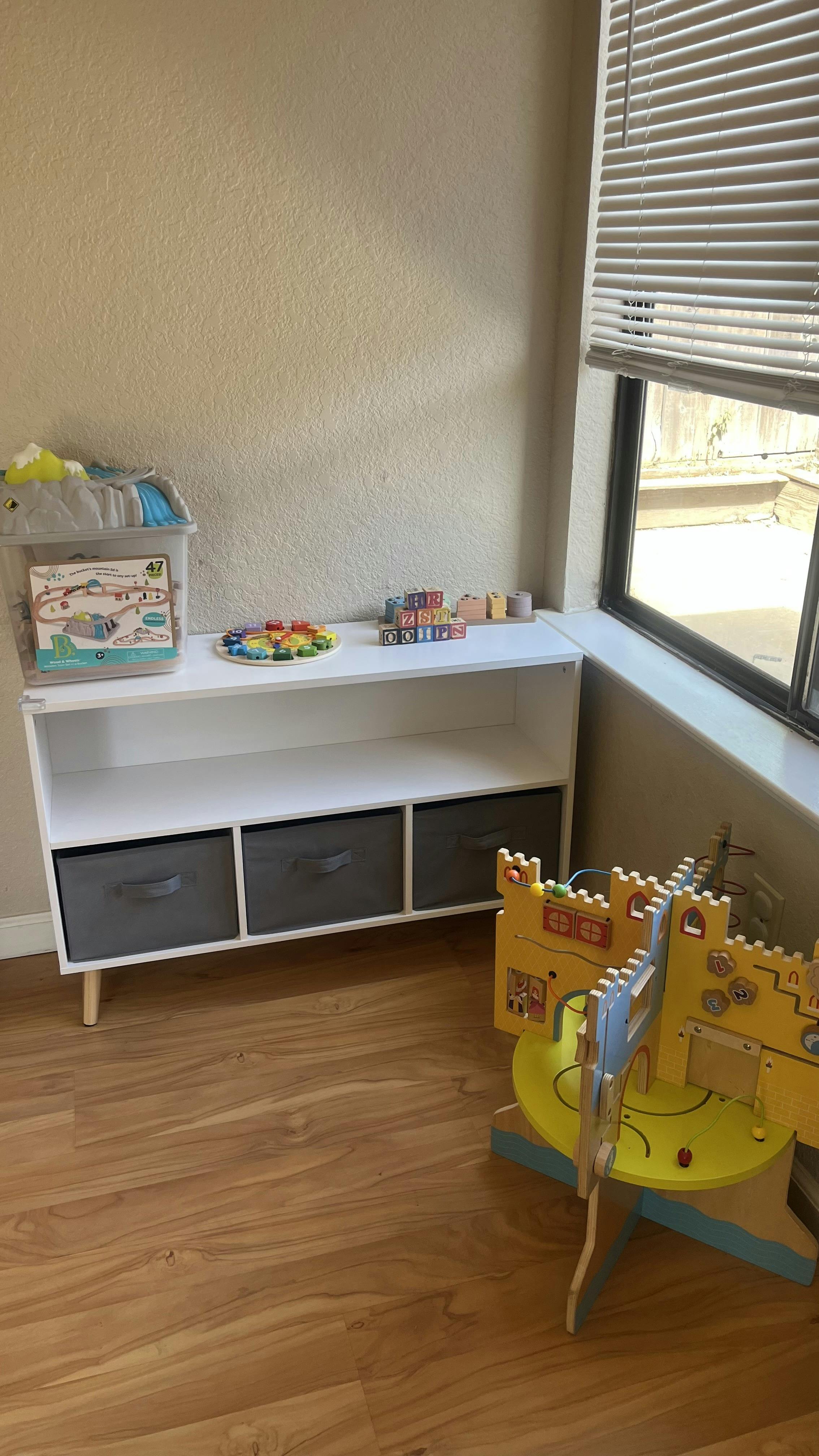 White shelving unit with gray bins and toys