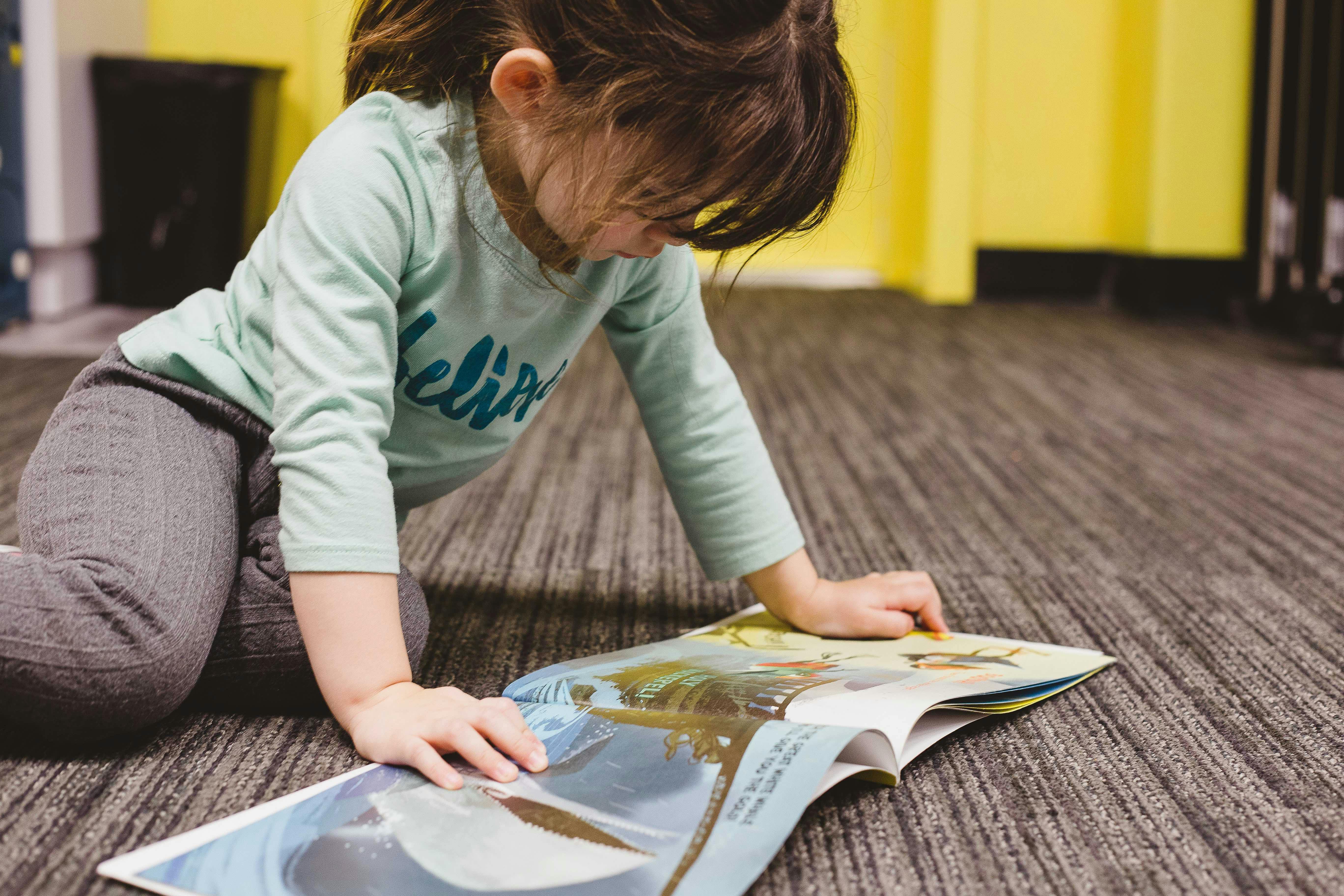 Child on floor looking at open book