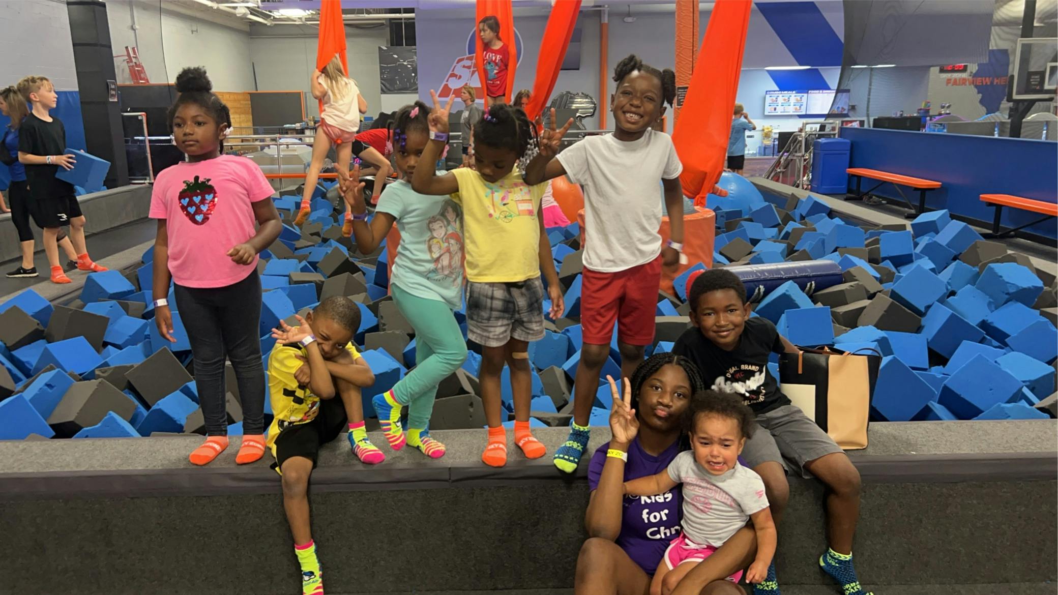 Group of children and adults posing in a foam pit area