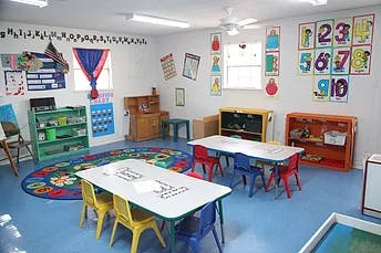 Classroom with small tables and chairs, shelves, and colorful decorations