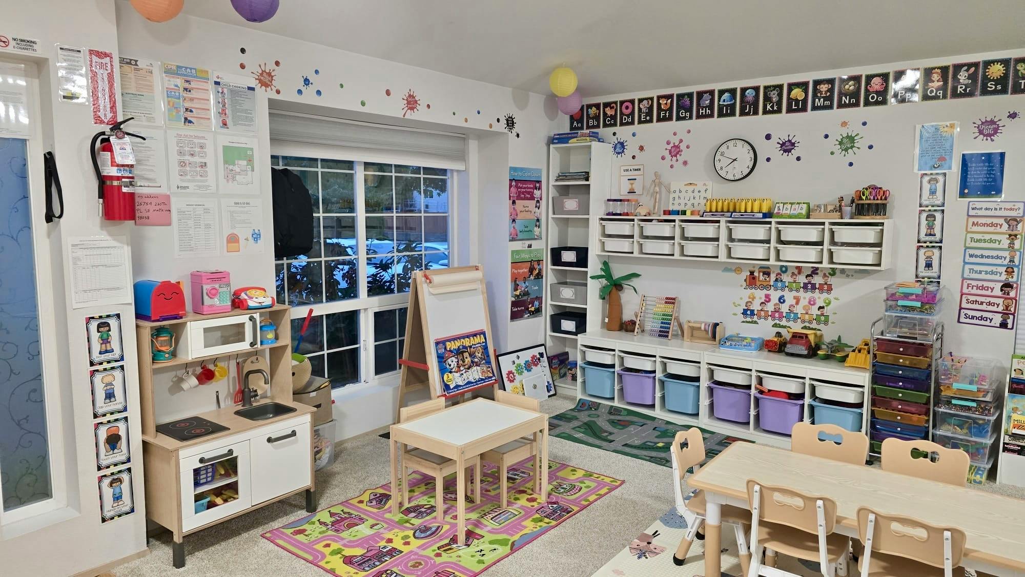 Childcare classroom with play kitchen and activity tables