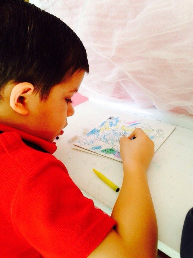 Child drawing on paper with a crayon