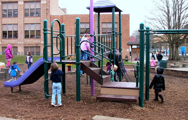 Children playing on a playground structure with slides and stairs