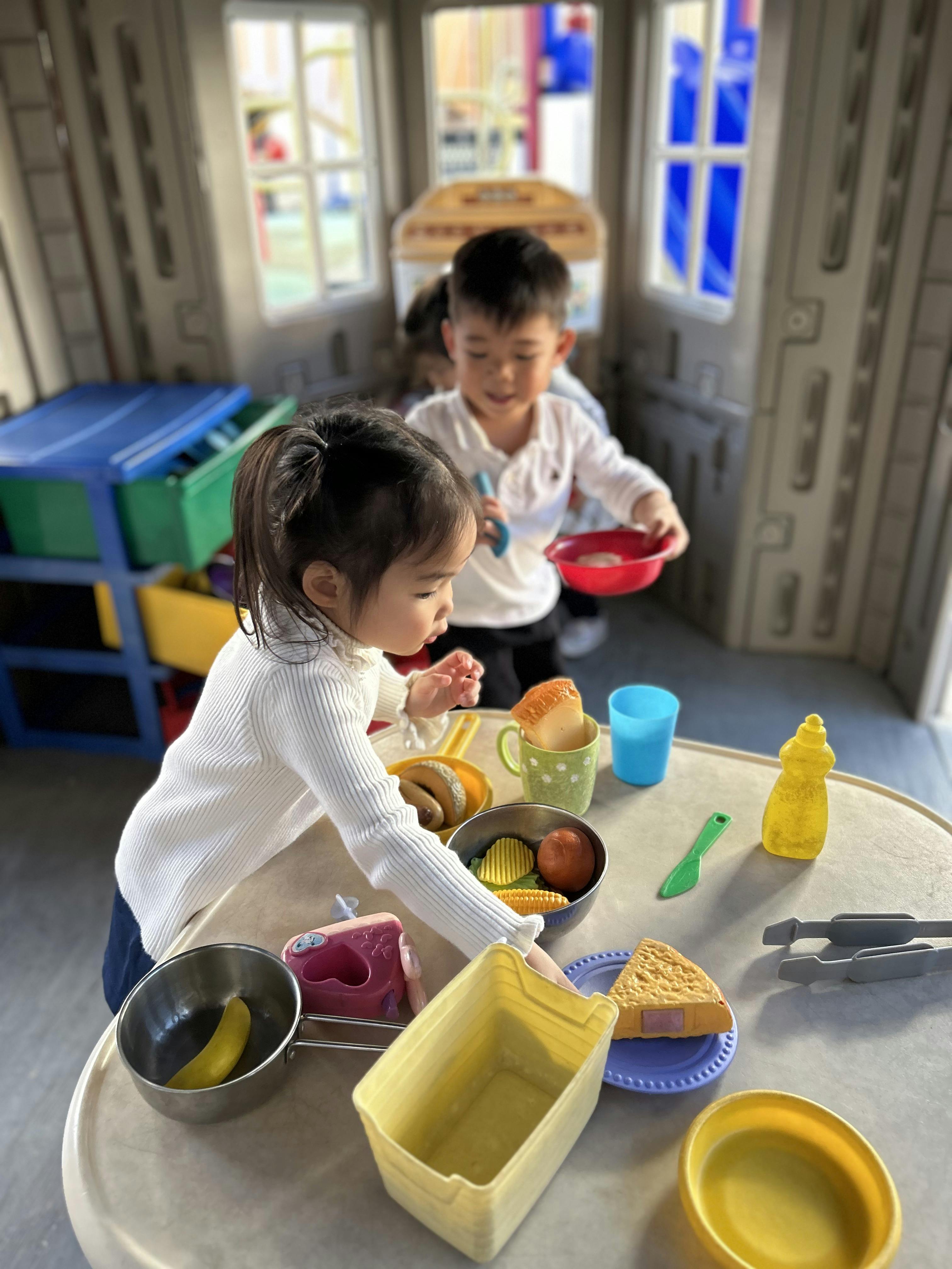 Children playing with toy food in a play kitchen
