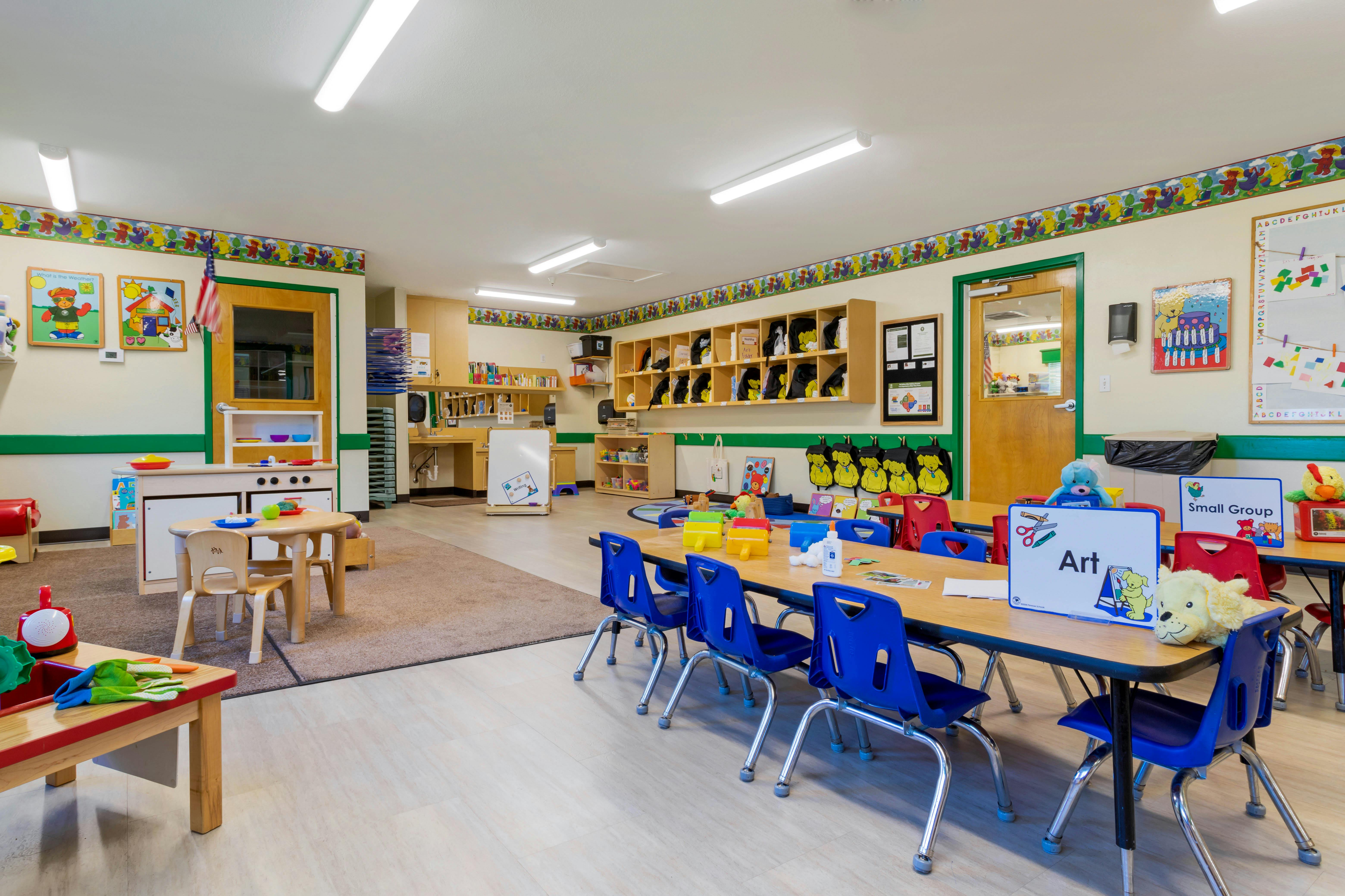 Classroom with child-sized tables and chairs, play kitchen, and cubbies