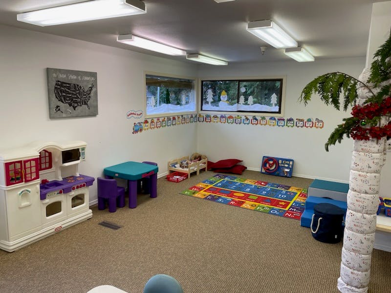 Playroom with toy kitchen, small table and chairs, and colorful rug