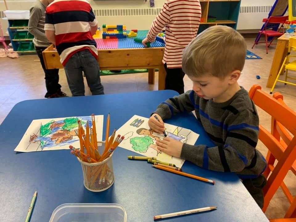 Child coloring at a blue table in a classroom