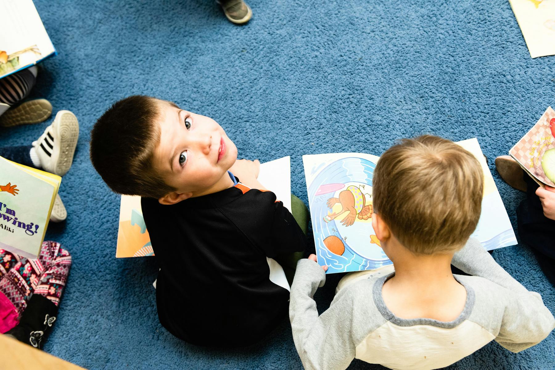 Two children reading books on the floor