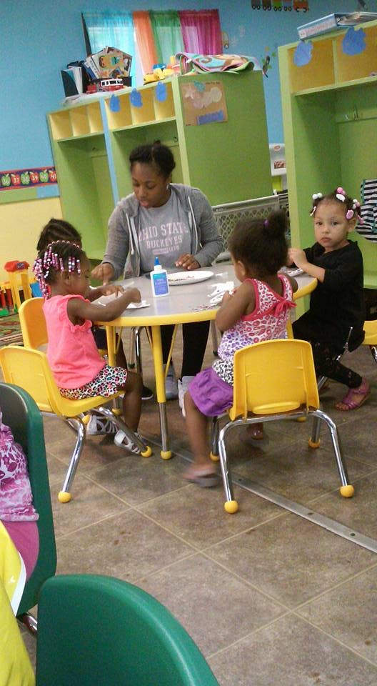 Adult and three children sitting at a small table in a classroom
