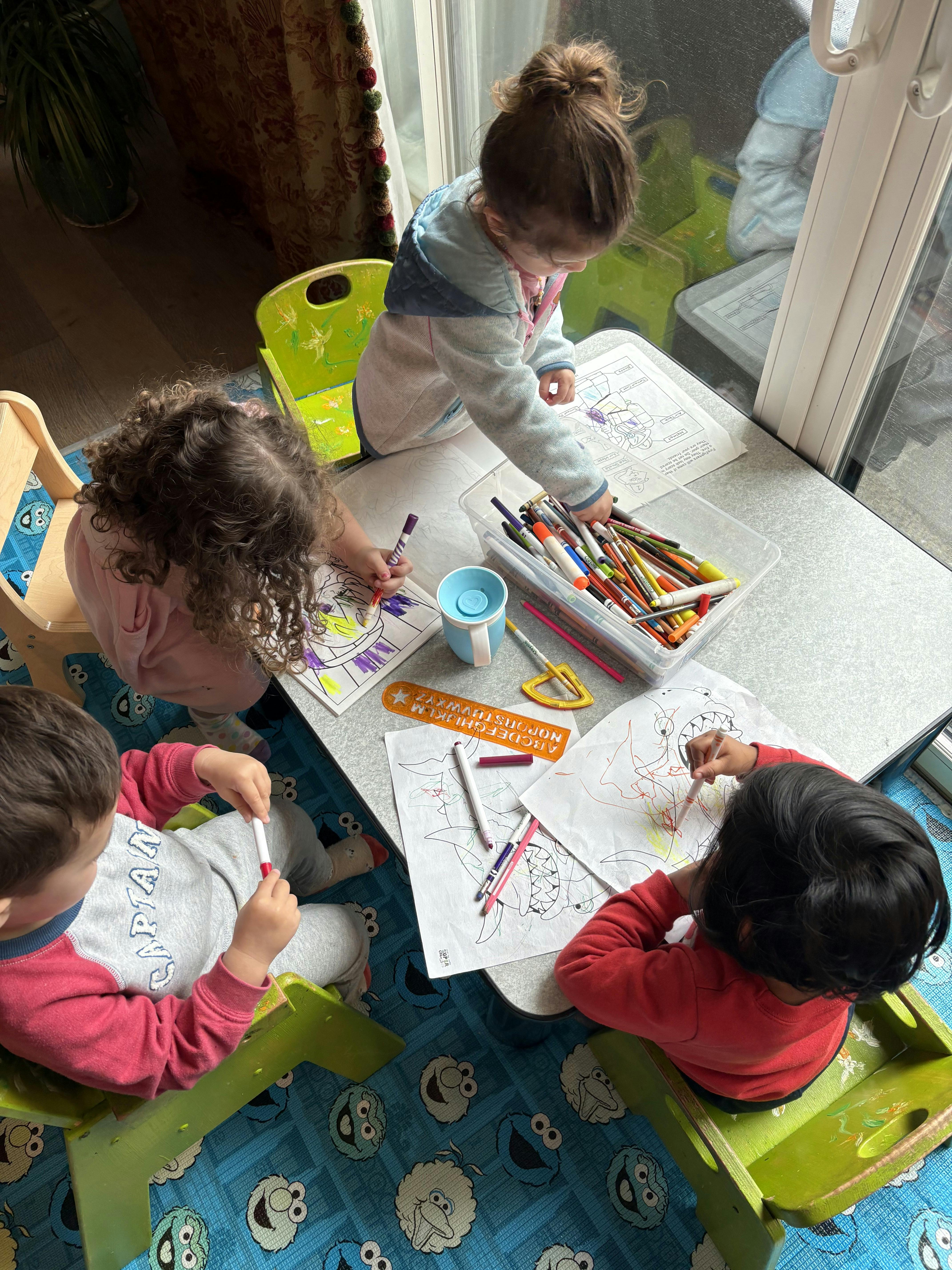 Three children drawing and coloring at a table