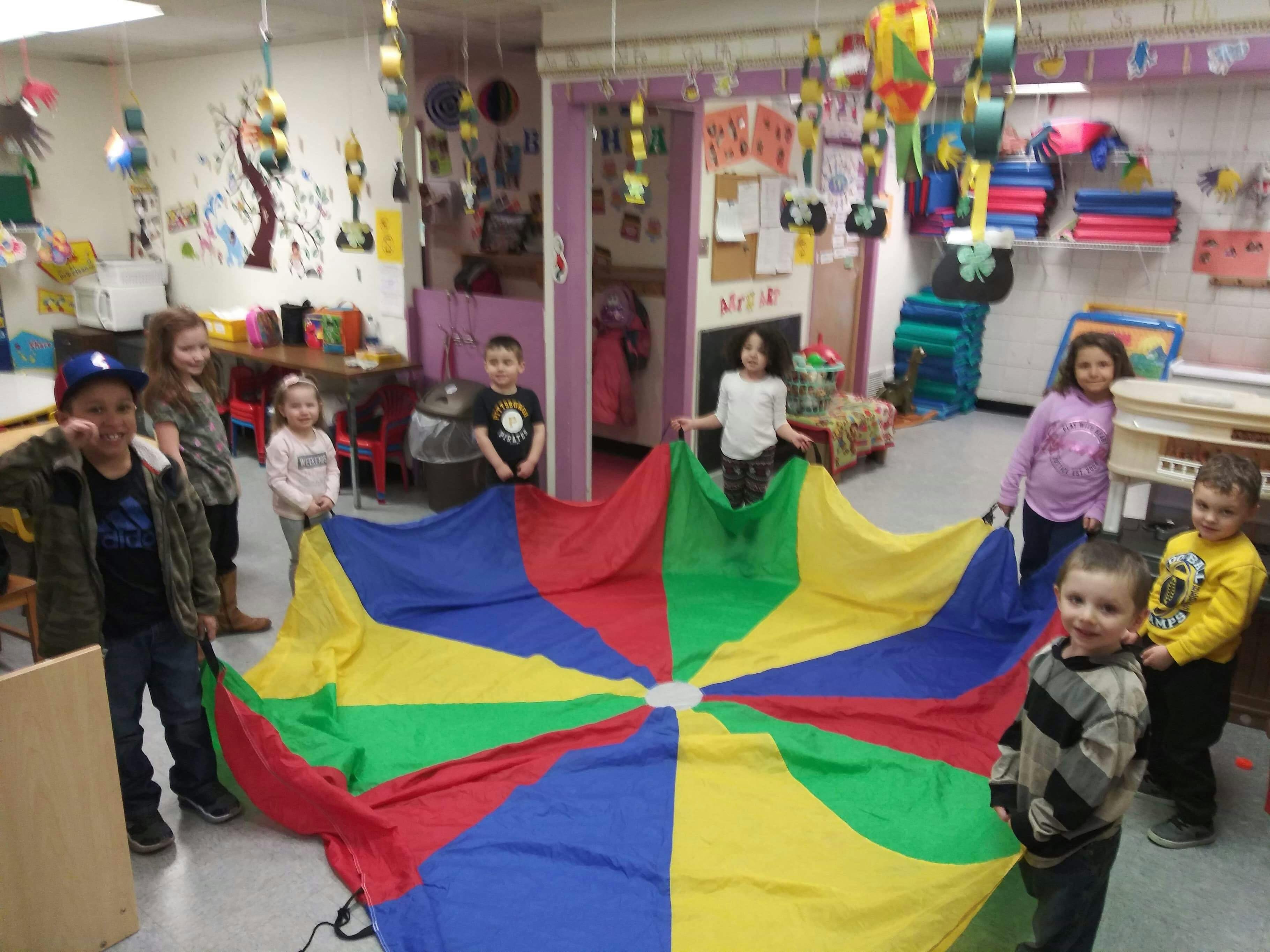Children holding a colorful parachute in a classroom