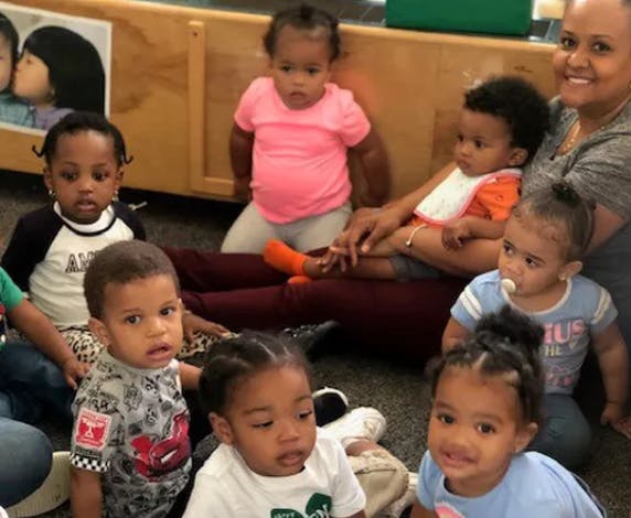 Group of young children and an adult sitting on the floor