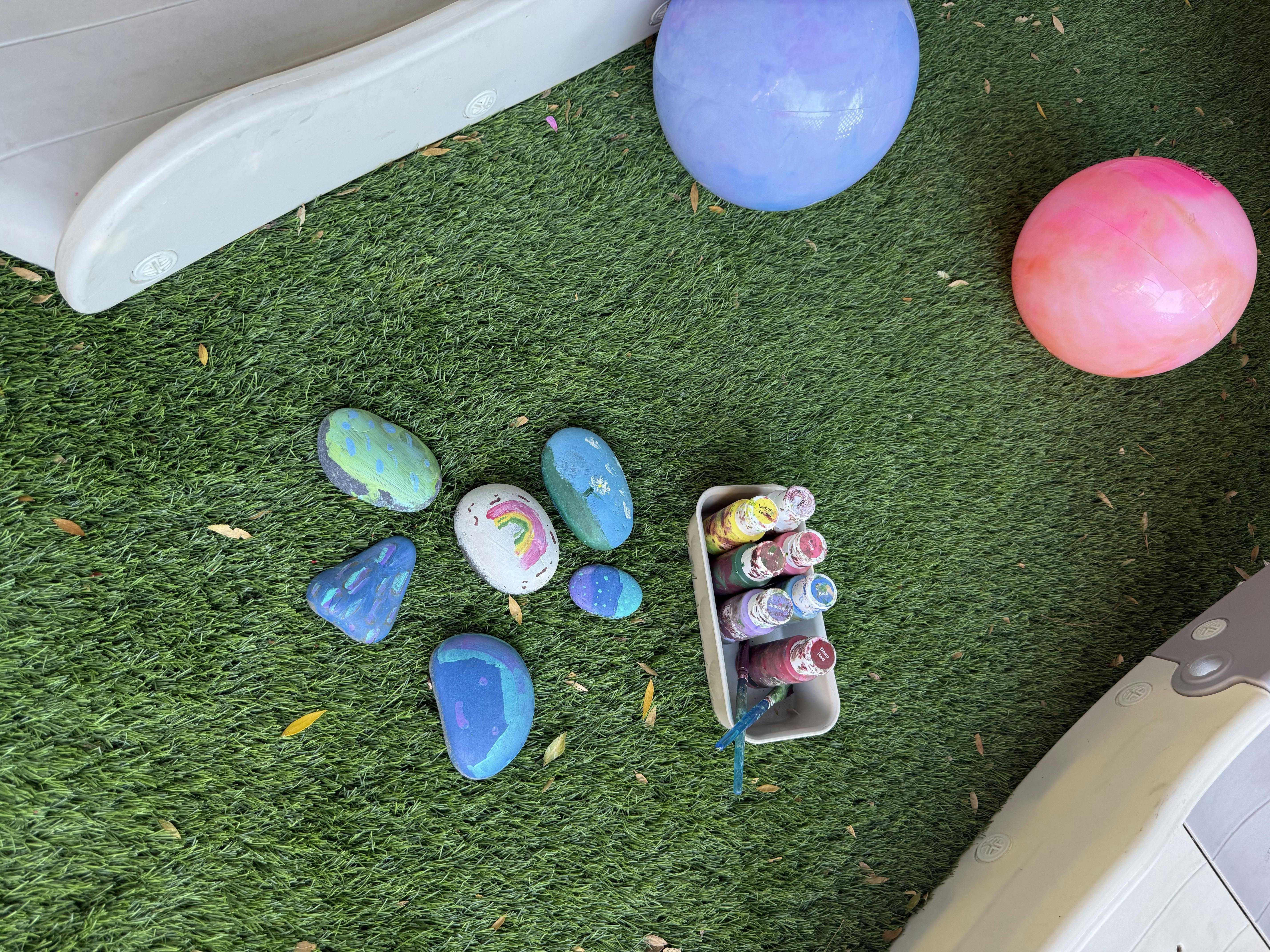 Painted rocks and paint pots on green grass