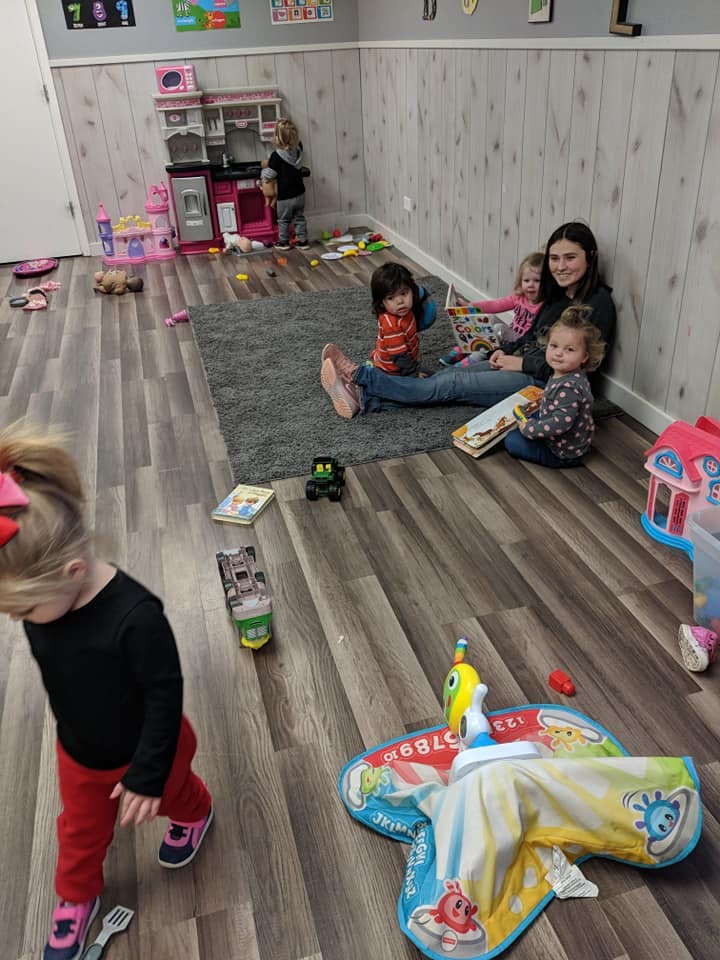 Person reading to three children in a playroom