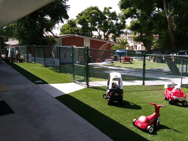 Toy cars on artificial grass in a fenced play area