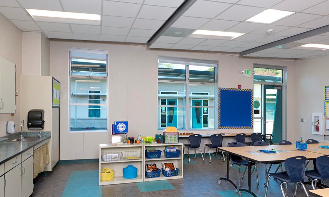 Empty classroom with tables, chairs, and a counter with a sink