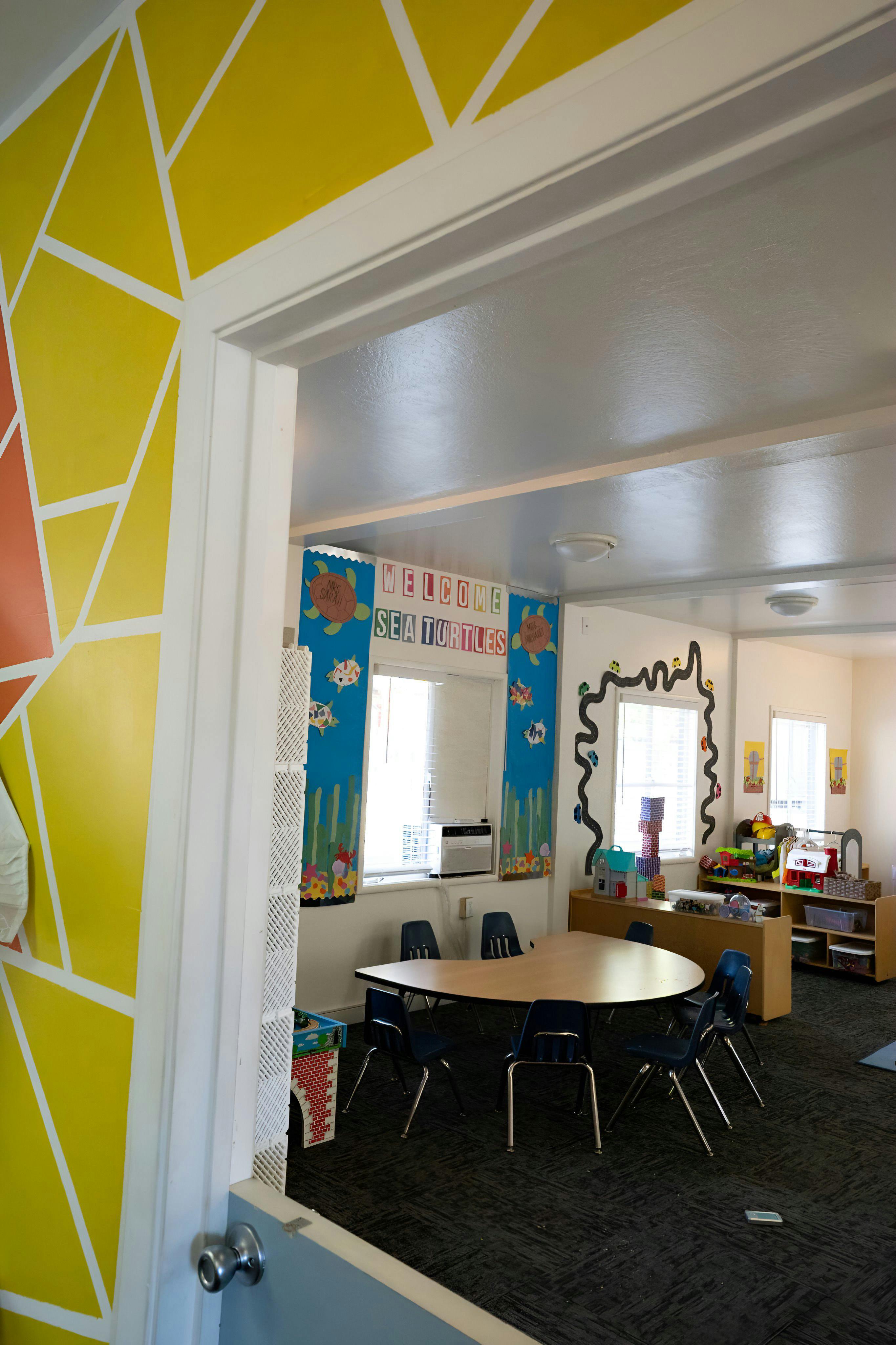 Classroom with a U-shaped table and chairs, decorated walls, and windows