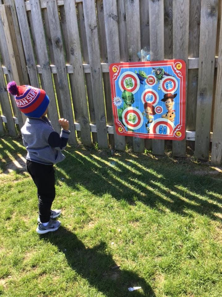 Child in a knit hat playing a target game outdoors