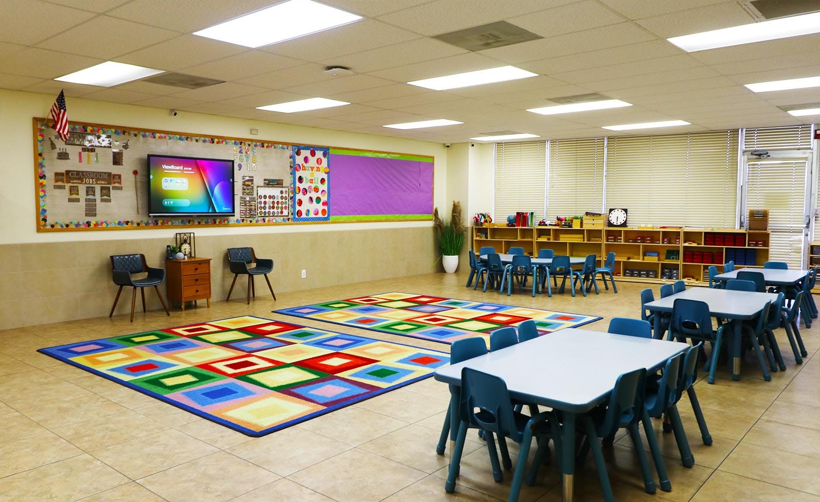 Classroom with colorful rugs, small tables, and chairs
