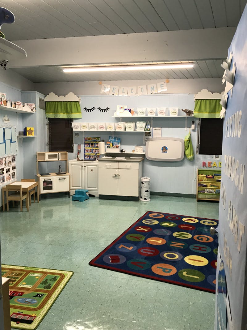Playroom with toy kitchen, small table and chairs, and alphabet rug
