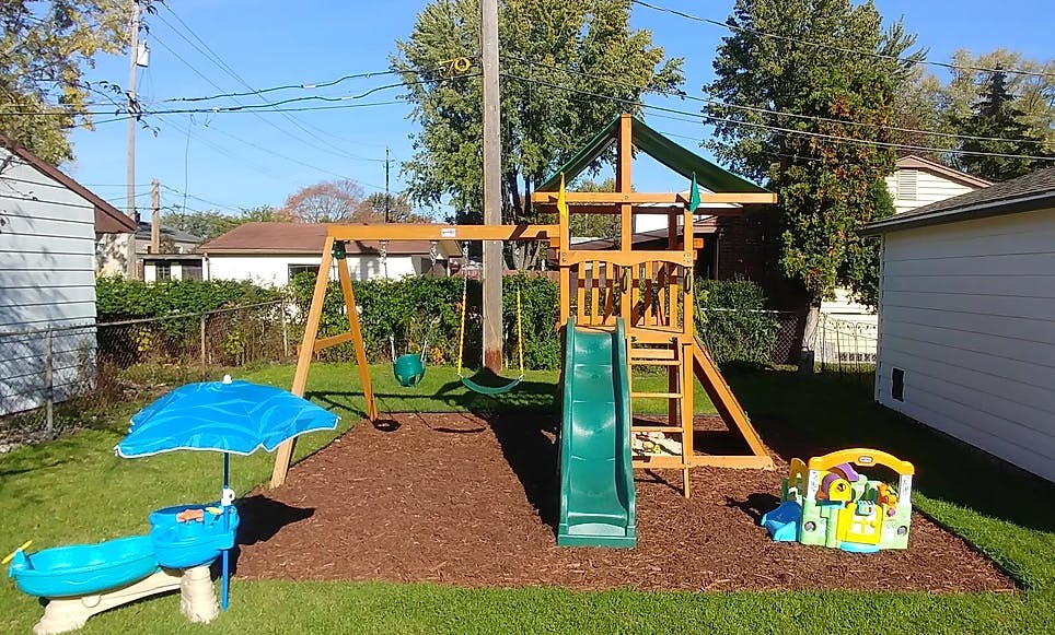Wooden playground set with swings and a slide in a backyard