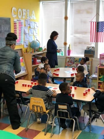 Adults and children in a classroom with red cups on tables