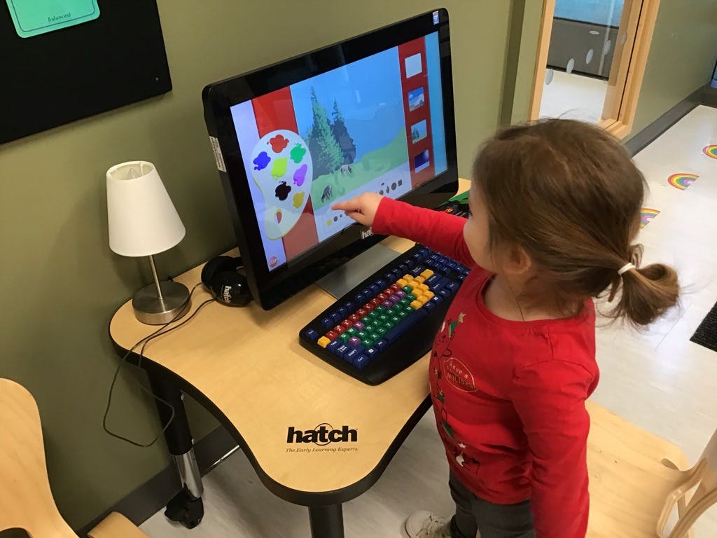 Child pointing at a computer screen with a colorful image
