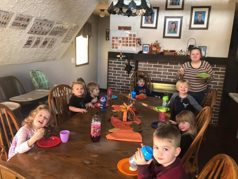 Adult and multiple children gathered around a dining table
