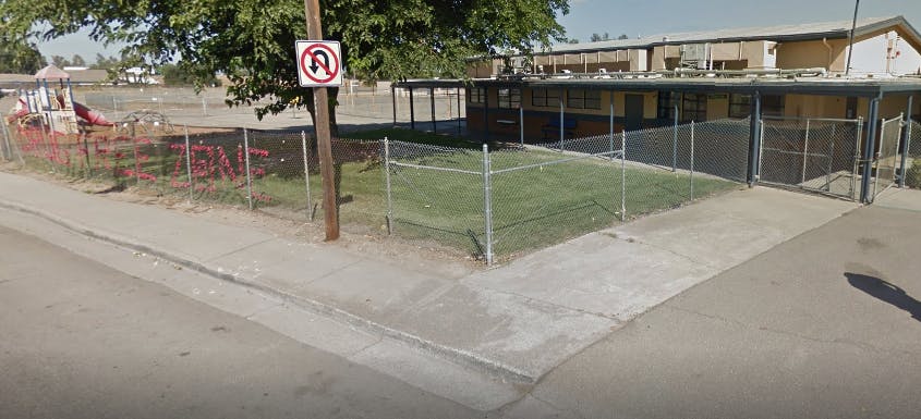 School building with a playground and a no U-turn sign