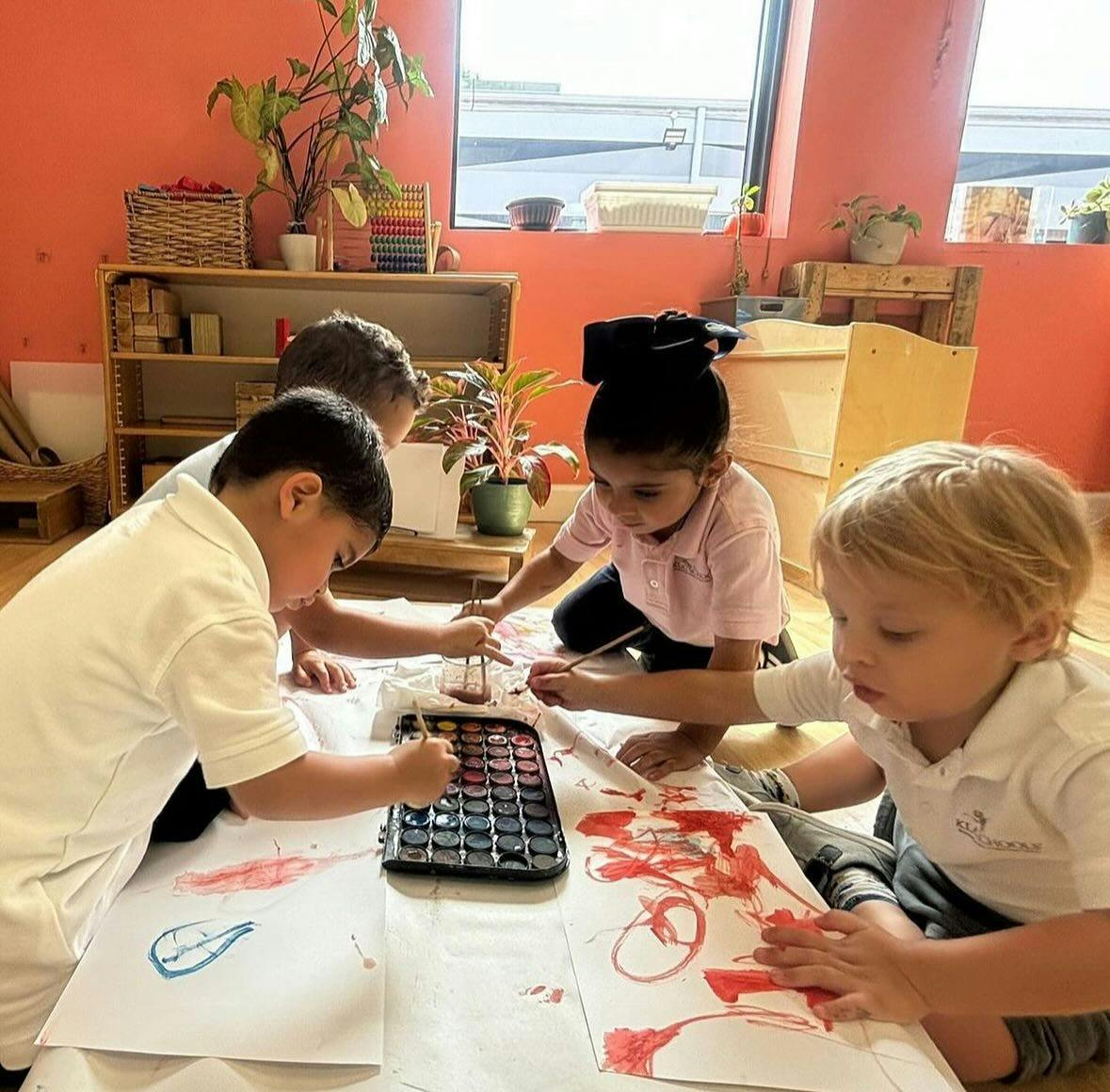 Children painting on paper on the floor