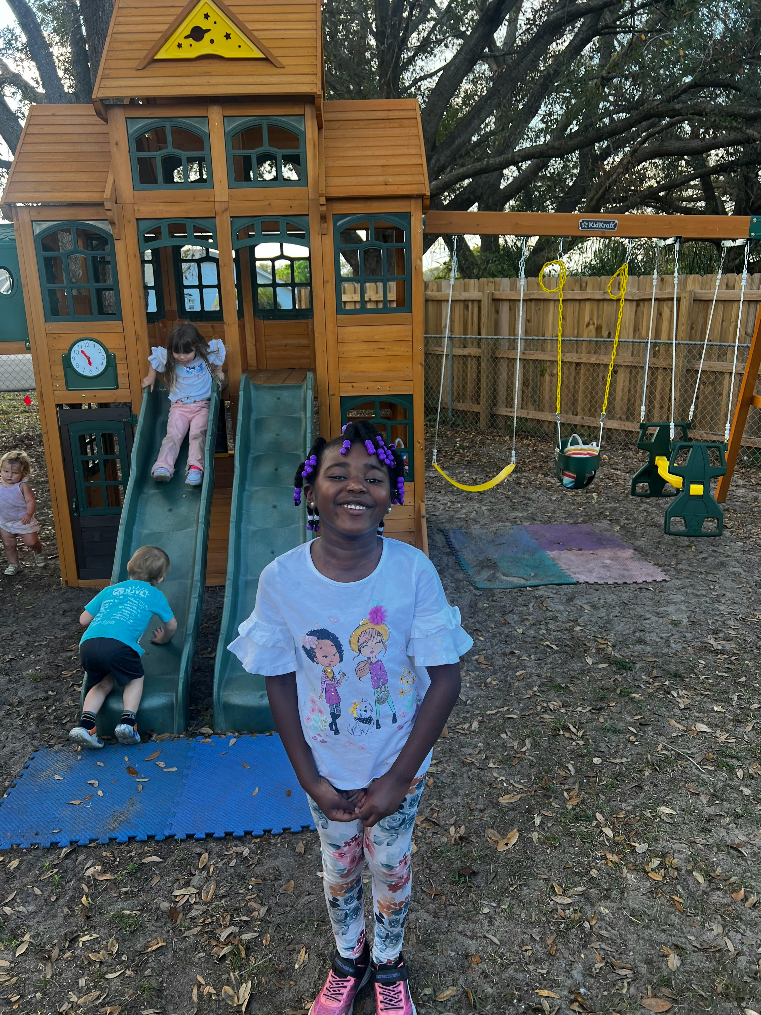 Child standing in front of a playground with other children