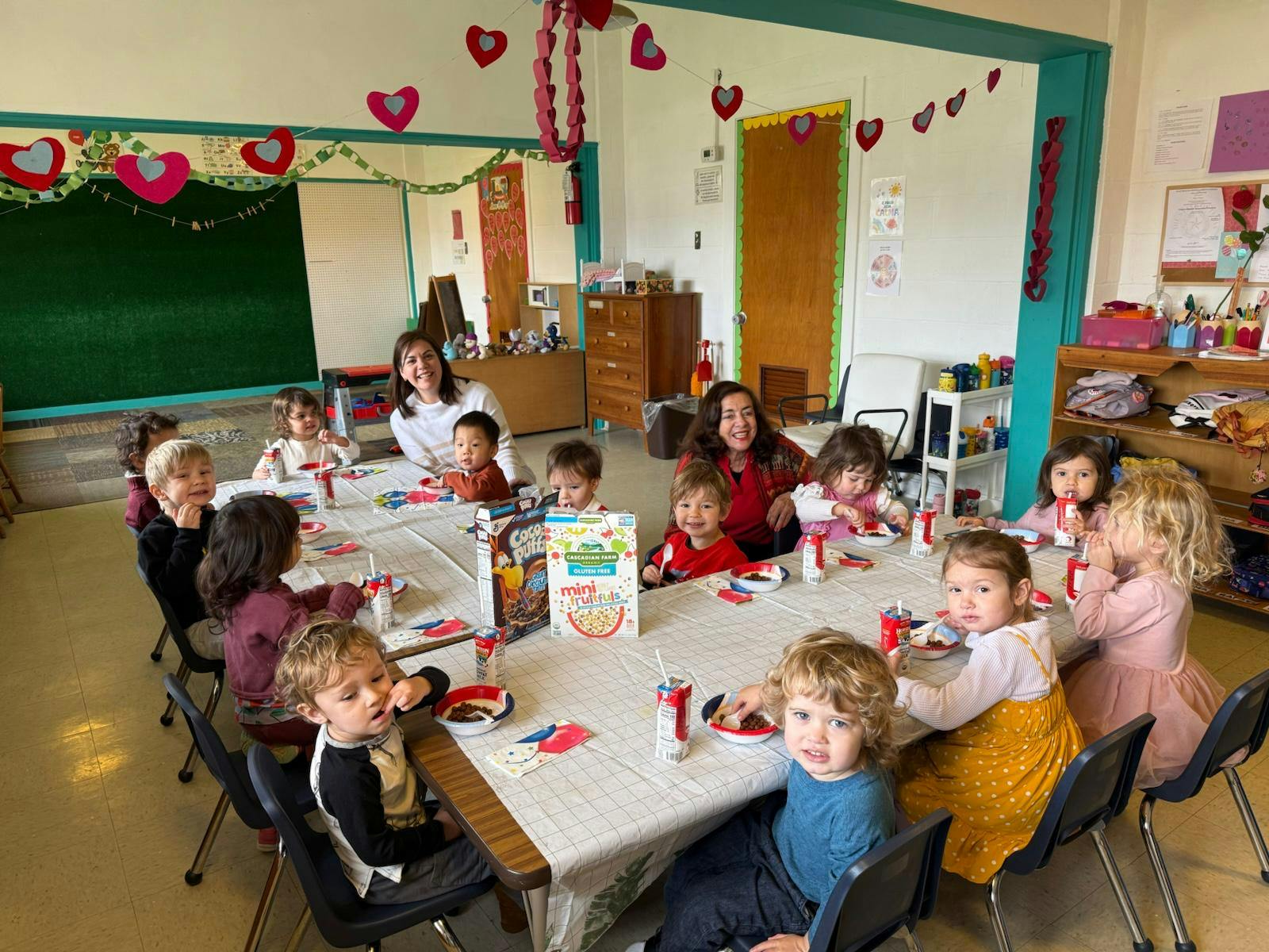 Adults and children sitting around tables in a classroom