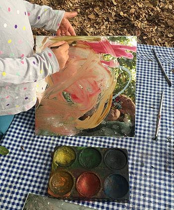 Child painting on a canvas outdoors