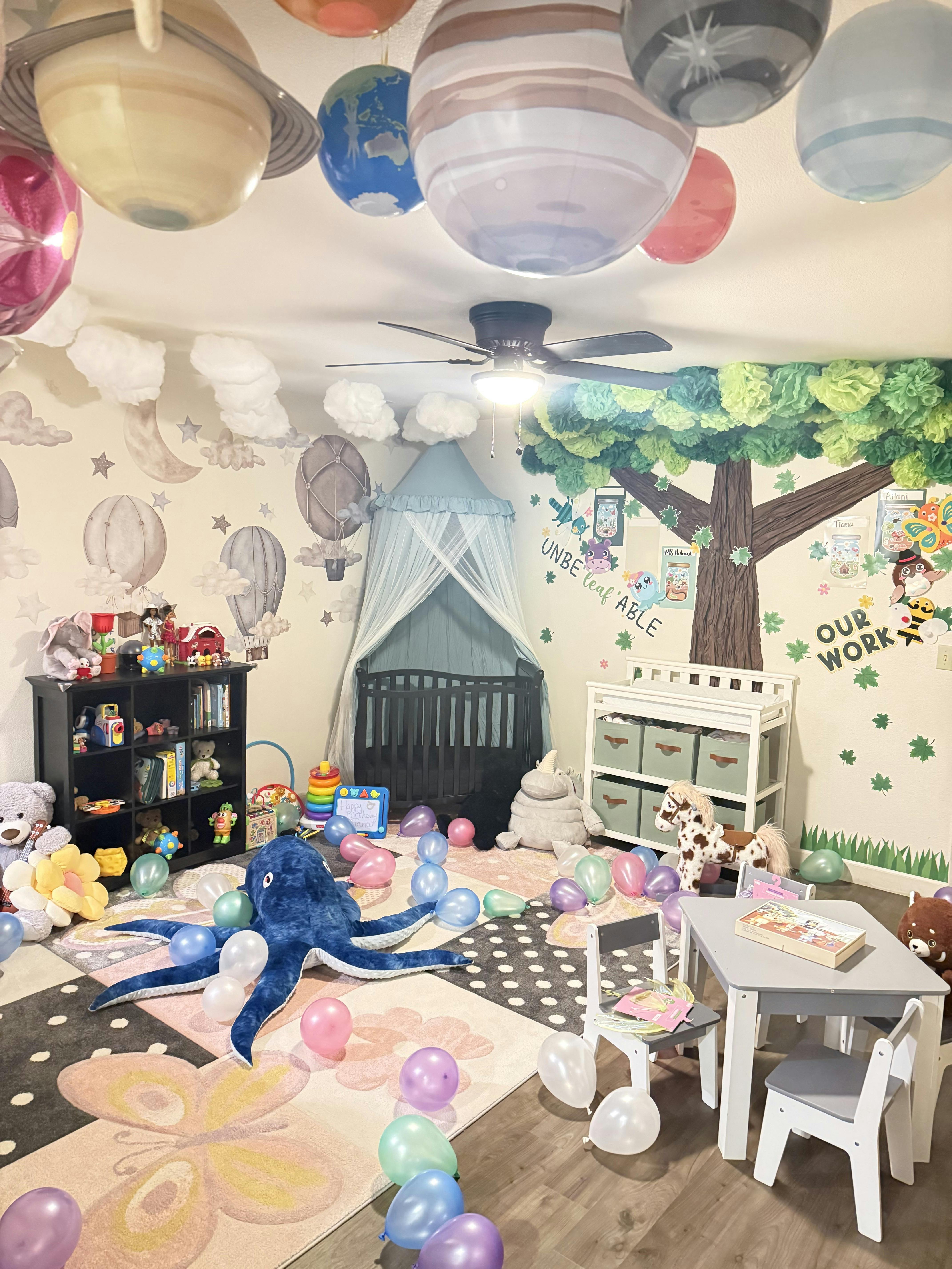 A colorful room decorated for a child with toys, a crib, and planet-themed ceiling decorations