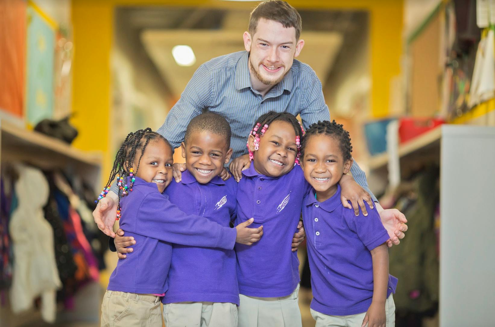 Adult person with four children in purple shirts