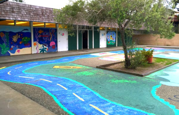 Outdoor school building with murals and painted playground