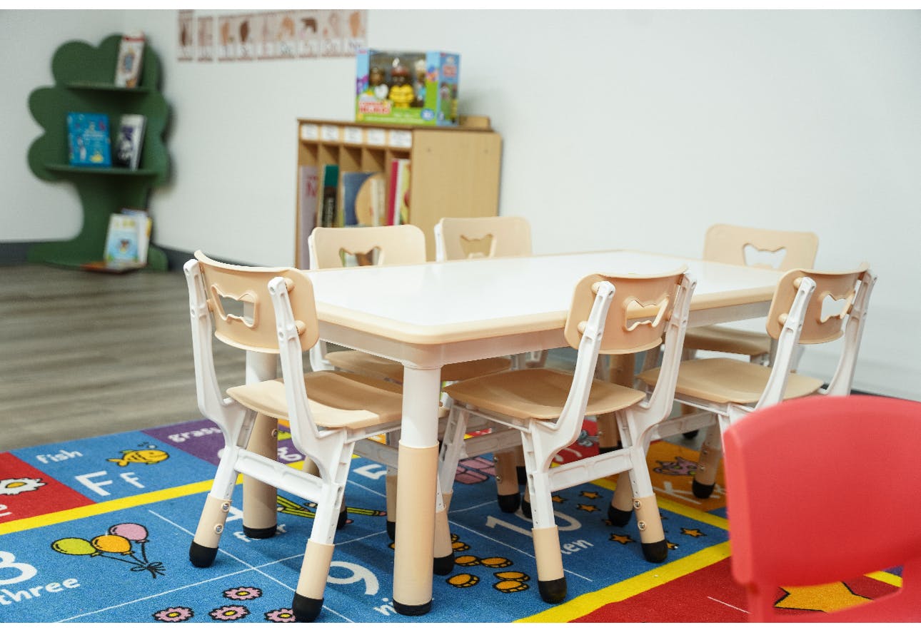 Empty classroom with small table and chairs on a colorful rug