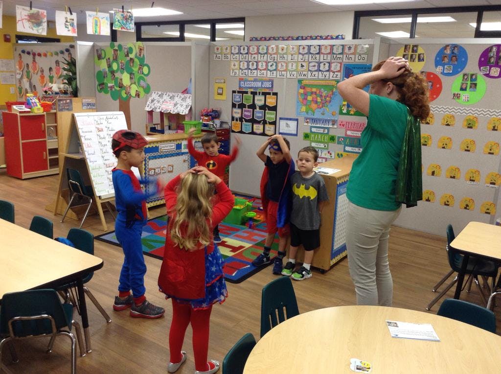 Adult and children in superhero costumes in a classroom