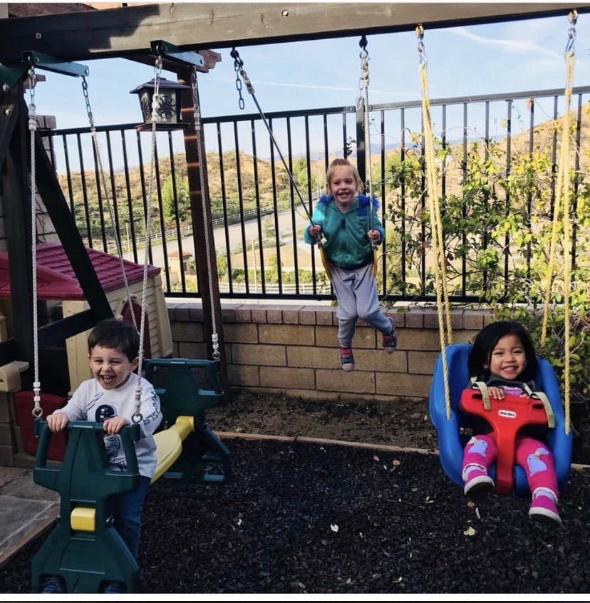 Three children playing on swings on a playground