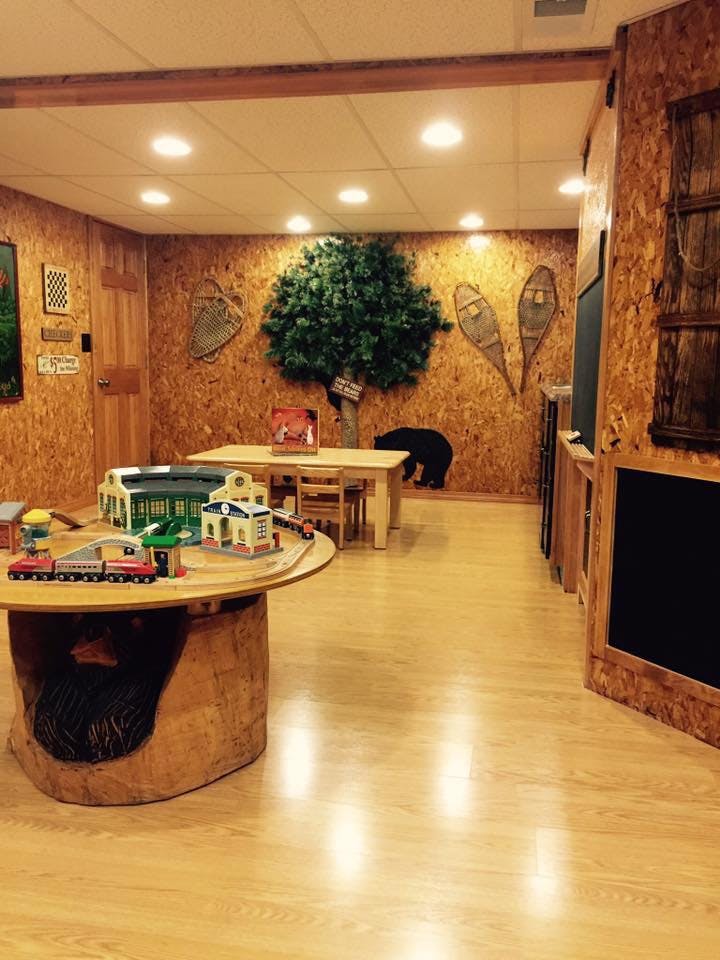 Playroom with a train set on a round table and a tree decoration on the wall