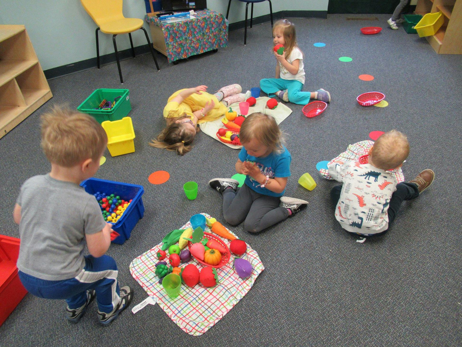 Children playing with toys on the floor in a classroom